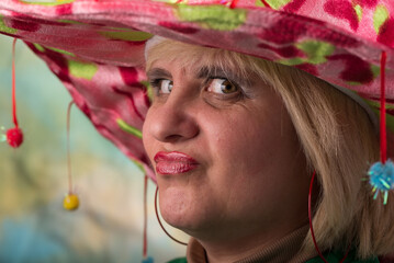 Clown in a hat. The buffoon grimaces and entertains. Portrait of a dressed up artist.