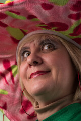 Clown in a hat. The buffoon grimaces and entertains. Portrait of a dressed up artist.