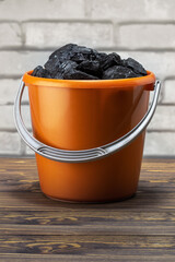 Coal pieces in the bucket on brick wall background. Cost of coal.