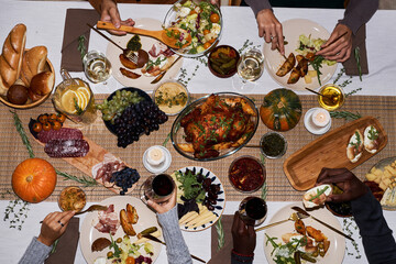 Top view background image of people at festive dinner table for Thanksgiving enjoying roasted...