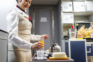 Beautiful Asian female cabin crew air hostess preparing food and drink beverage to serve passengers...