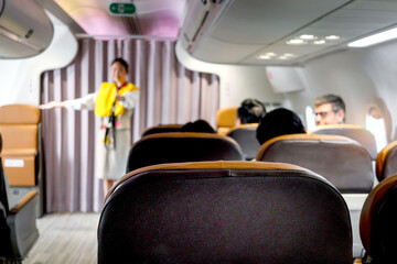 Seats in cabin airplane with blurred background of cabin crew air hostess show safety rules before...