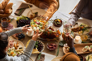 Multiethnic group of people at festive dinner table celebrating Thanksgiving together and enjoying...
