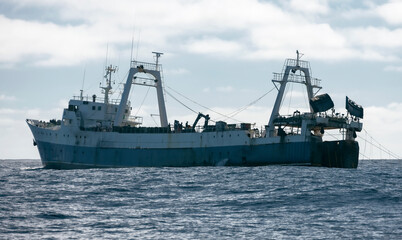 Large fishing trawler catches sea fish and seafood in ocean waters.