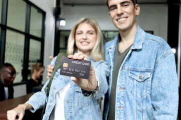 Beautiful woman traveler with long blonde hair showing credit card to camera went checking in at hotel reception counter desk, happy couple lover checks in at hotel on romantic holiday vacation.