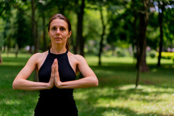 an experienced female instructor meditates in the park practices yoga does stretching and exercises for different muscle groups