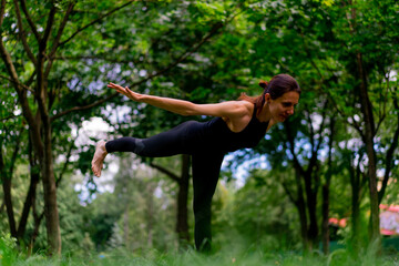 an experienced female instructor meditates in the park practices yoga does stretching and exercises for different muscle groups