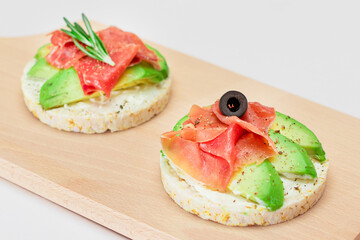 Rice Cake Sandwich with Avocado, Jamon, Olives and Rosemary on Wooden Cutting Board. Easy Breakfast. Quick and Healthy Sandwiches. Crispbread with Tasty Filling. Healthy Dietary Snack