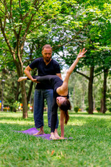 Fototapeta premium a male yoga instructor conducts a class with a woman in the park in the fresh air couple exercises spiritual practices