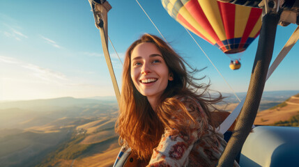 Young woman in a high-altitude hot air balloon , she's in the gondola of a colorful balloon, floating gracefully over picturesque landscapes - obrazy, fototapety, plakaty