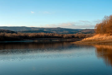 Panoramic landscape from the lake with colorful clouds in the summer sun.