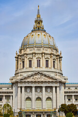 Fototapeta premium Close up of city hall entrance with focus on gilded dome and white pillars above doors