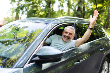 Nice middle age man greeting someone while driving