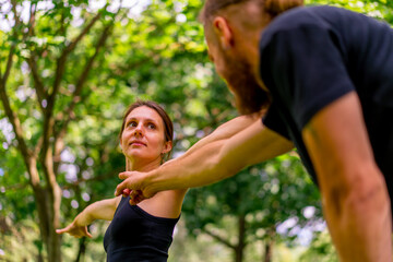 a male yoga instructor conducts a class with a woman in the park in the fresh air couple exercises...