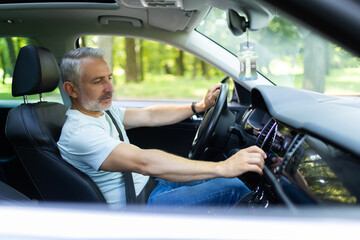 mid age man driver turning on radio in auto, over shoulder shot, copy space.