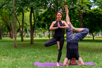 couple in love or yoga instructor and woman doing exercises in city park asana spiritual practice...