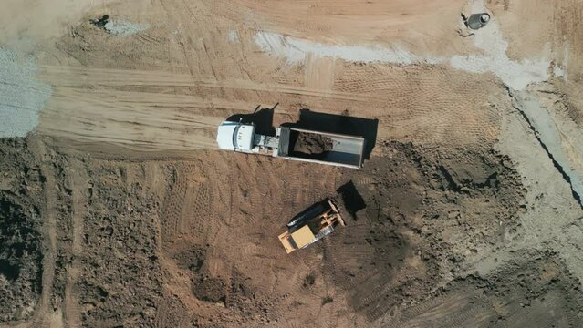 Drone footage. A bulldozer levels a plot of land for construction development. Above shot