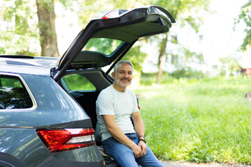Middle aged man examining car trunk at showroom.