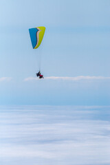 paragliding in the blue sky above the clouds