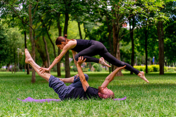 couple in love or yoga instructor and woman doing exercises in city park asana spiritual practice...