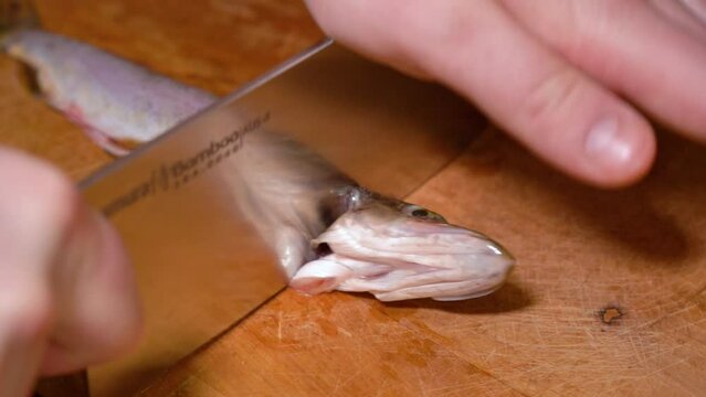 the process of cutting a small pike on a wooden board