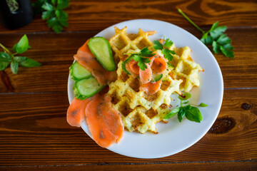 Cooked potato waffles with lightly salted red fish and herbs in a plate.