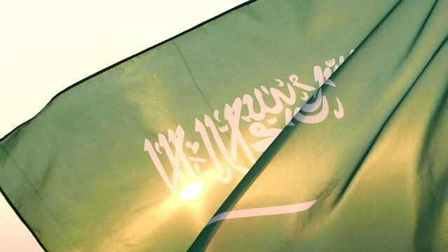 Saudi National Day. Saudi Arabia flag waving in sky against wind, beautiful sunset or sunrise outdoor backgrounds, slow motion. Concept of Saudi Arabia, Independence Day, Celebration, Holiday, Flag