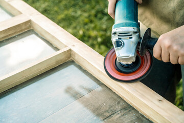 Wood sanding, furniture restoration and restoration. A carpenter sands an old window in his...