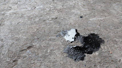 Abstract black engine oil drop on concrete floor texture backgruond.
Automobile garage dirty old oil stain cement pattern.  