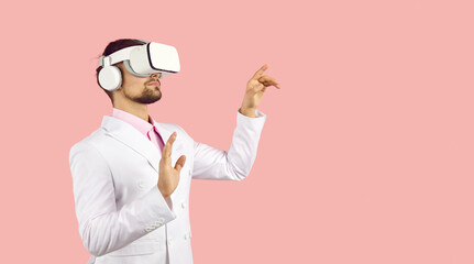 Serious man in suit and VR gear headset innovation experiences virtual reality, pushes buttons,...