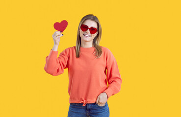Beautiful woman wishes you a happy Valentine's Day. Cheerful young girl in heart shaped glasses...