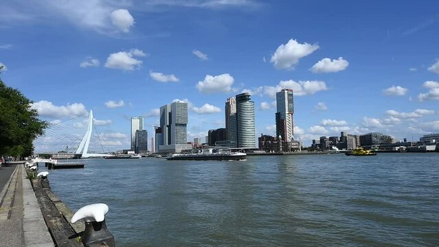Rotterdam on a sunny day showing busy shipping activity on the Nieuwe Maas with vessels passing under the Erasmusbrug and in front of the cruise terminal and Hotel New York