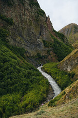 Georgia, Kazbegi region. View of the green mountains and the stormy Terek River in the gorge. Amazing autumn landscape of the national Park. Tourist route to the Truso Valley, Caucasus mountains.