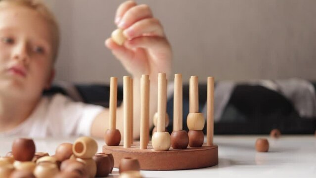 logic wooden board game and a boy playing with it close-up