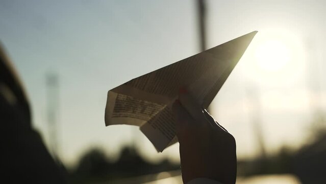 Young woman in beige coat playing with paper airplane at train station in autumn