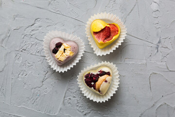 chocolate sweets in the form of a heart with fruits and nuts on a colored background. top view with space for text, holiday concept