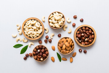 Assortment of nuts in wooden bowl on colored table. Cashew, hazelnuts, walnuts, almonds. Mix of nuts Top view with copy space