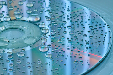 Calm blue and silver surface with silvery water droplets on CD surface and slate blue background