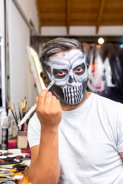 Latin Man Putting On Makeup To Celebrate Halloween Or Days Of The Dead