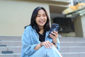 cheerful asian young woman remote worker laughing enjoy using smartphone surfing on social media,...