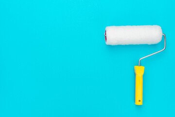 Clean paint roller on the turquoise blue background with copy space.