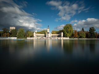 Fototapeta premium Monument to Alfonso XII with a lake with boats in front at a sunset with clouds