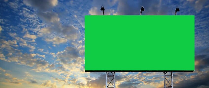 Wide blank  green billboard or large display and moving white clouds against blue sky. It's feel like consumerism, time lapse, advertising, template, mock up, copy space and chroma key concept. 