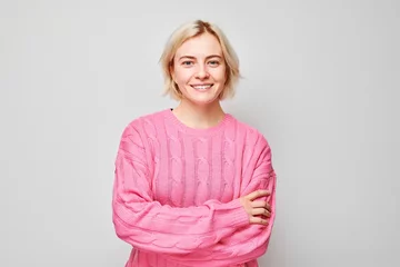 Foto op Plexiglas Portrait Caucasian young blond woman smiling joyfully isolated on white studio background. Happy girl in pink sweater with glad face expression © amixstudio
