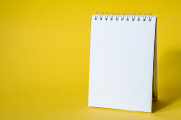 Opened notepad on a yellow background. Composition of writing to-dos for the day. The notebook lies on a plain background with space for writing. 