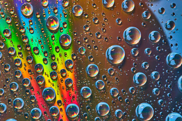 Brilliant slash of rainbow light across silver metal surface with rainbow flames inside waterdrops