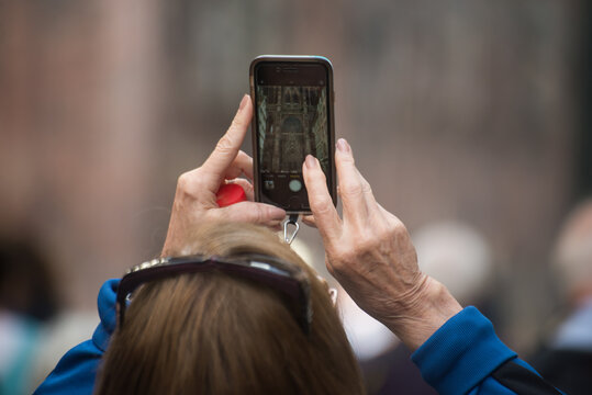 Closeup of hands of old woman taking a photo with her smartphone in the street