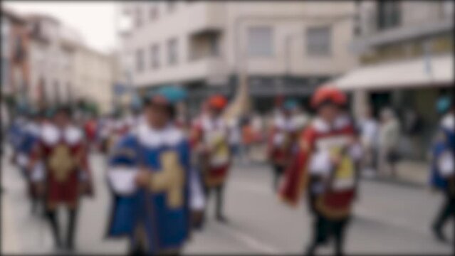 Holiday in the Spanish city of Astorga, musketeers in blue and red suits with muskets are walking along the street. Background, blurry video.