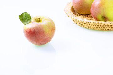 Ripe apple and a basket of apples on a white background
