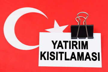 On the flag of Turkey lies a business card with the inscription - investment restriction